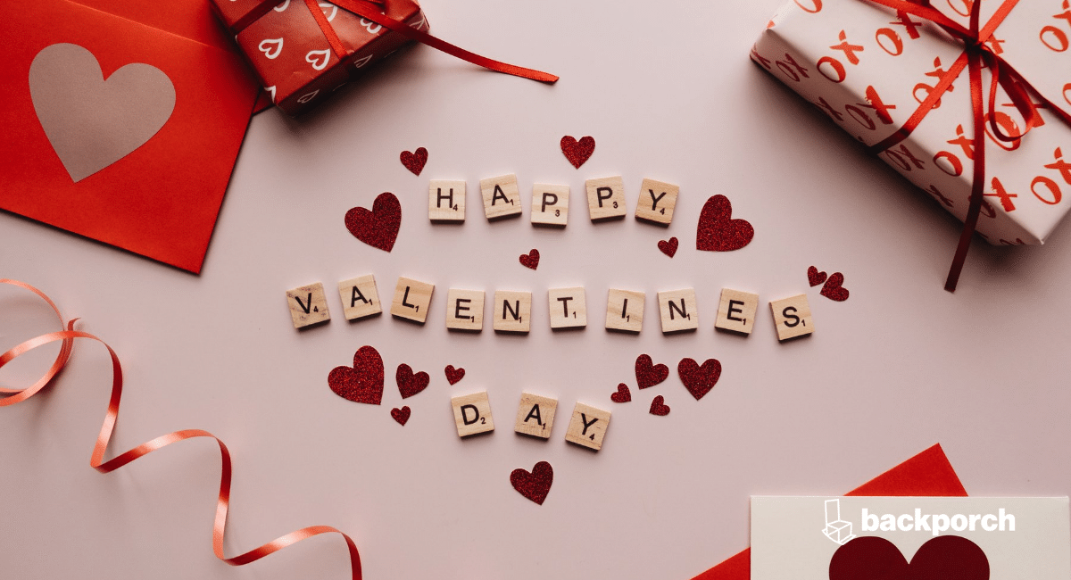 Tabletop with wrapped gifts, greeting cards, and the words Happy Valentines Day spelled out in Scrabble letter tiles.