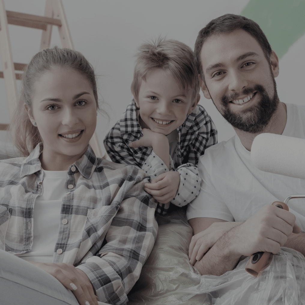 A man, woman, and child posing for a picture in front of a step ladder while painting an interior room.