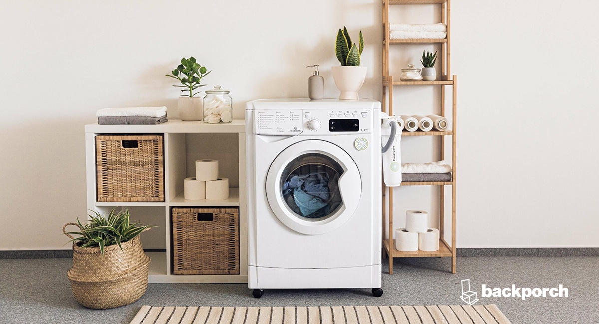 A laundry room with a washing machine and storage shelves and baskets.