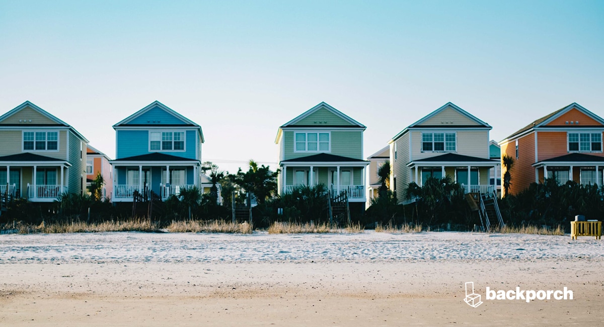 A row of colorful beach houses on the sand.